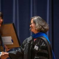 President Mantella shakes hands and presents woman with large certificate award